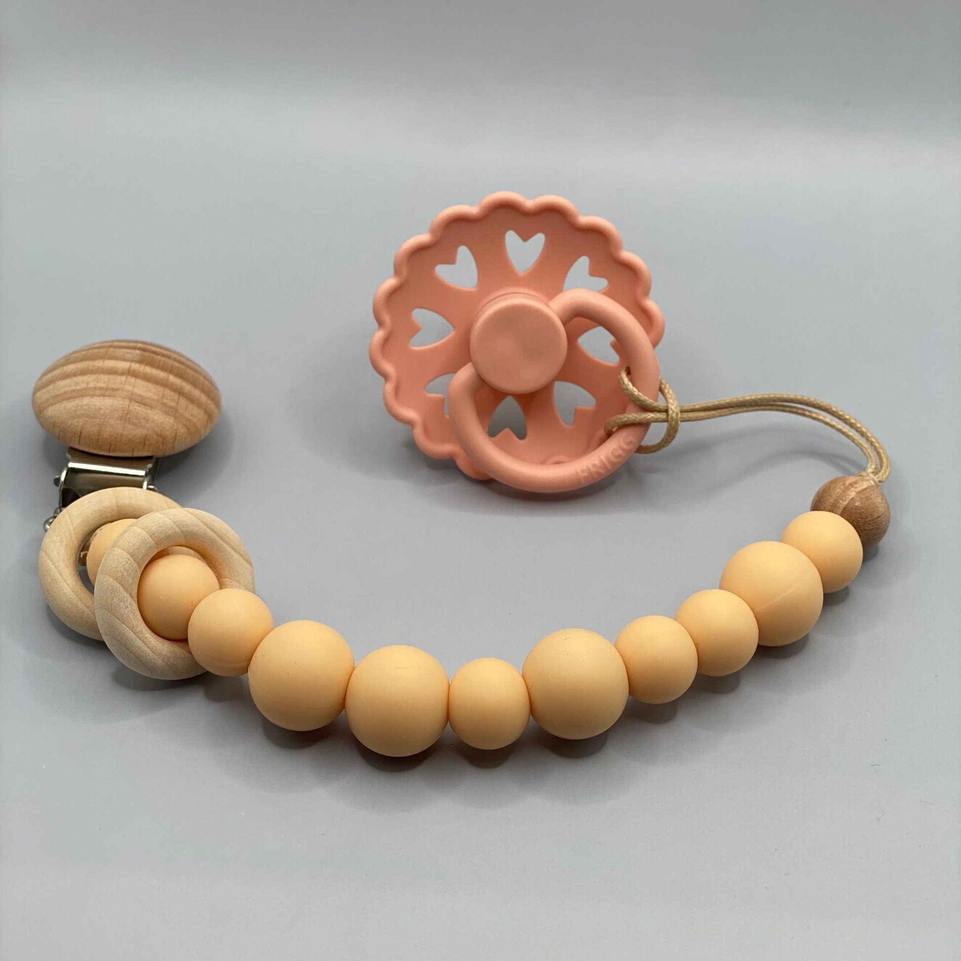 Teething ring with wooden beads and clip on a gray background