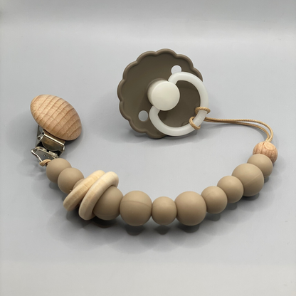 Teething necklace with wooden beads and a pacifier clip on a gray background